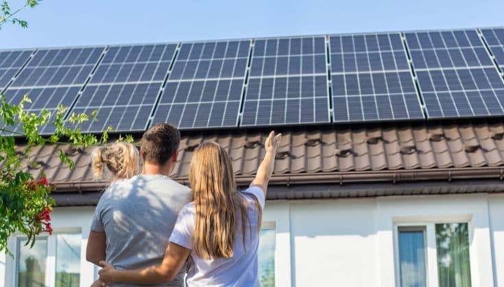 Famiglia che guarda i pannelli fotovoltaici sul tetto di casa