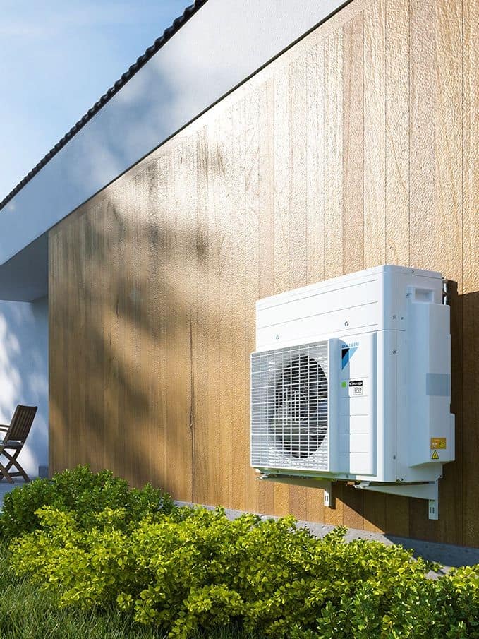 Unità esterna di una pompa di calore staffata alla parete di una casa