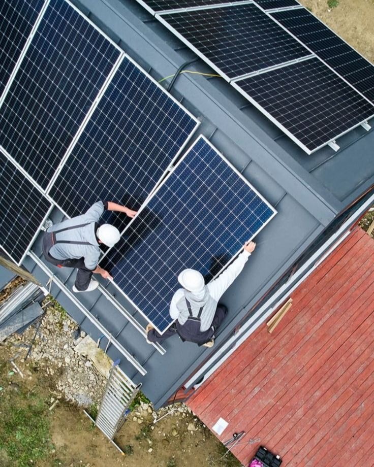Due installatori che posano i pannelli fotovoltaici, visti dall’alto